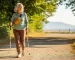 Modern aktív 70-es magyar nő (Loncika) nordic walking botokkal egy magyar park-túraúton, derűs reggel